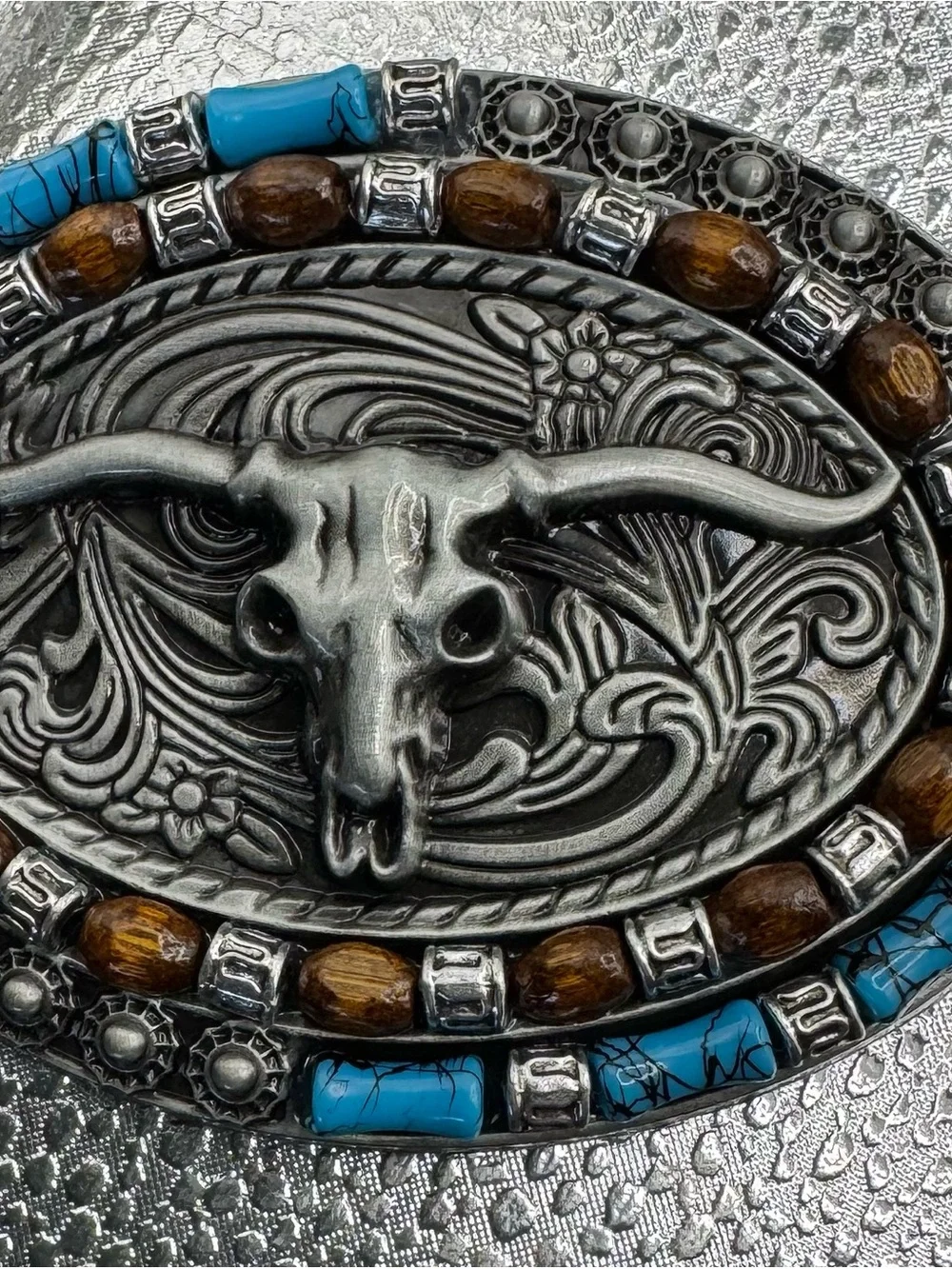 style longhorn skull belt buckle paired with a brown embossed leather strap.